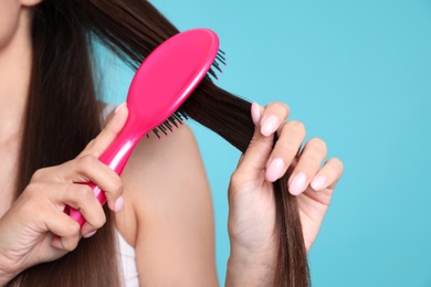 Photo of Woman with hair brush on color background, closeup. Space for text