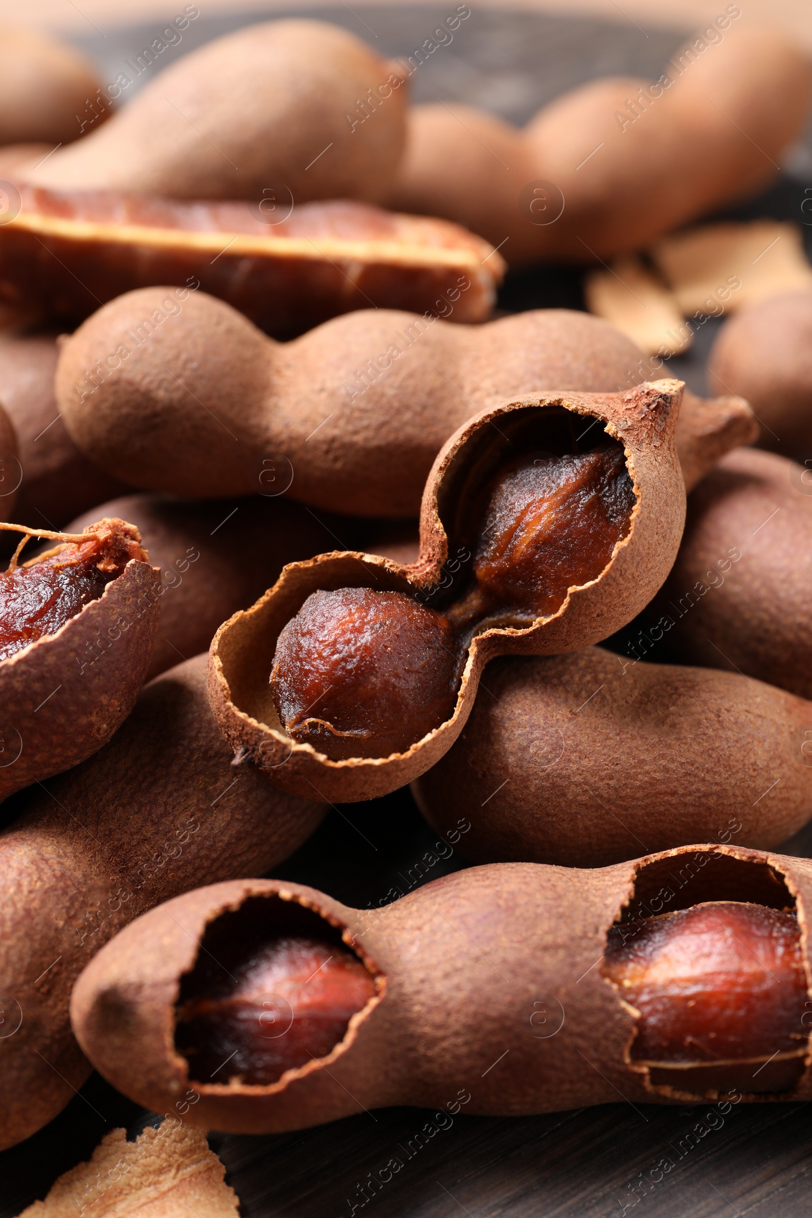 Photo of Delicious ripe tamarinds on wooden board, closeup