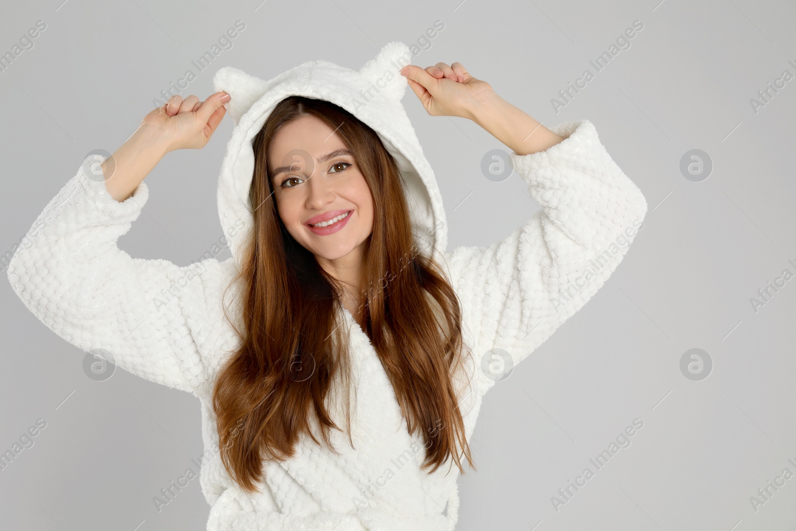 Photo of Beautiful young woman in bathrobe with funny hood on light grey background