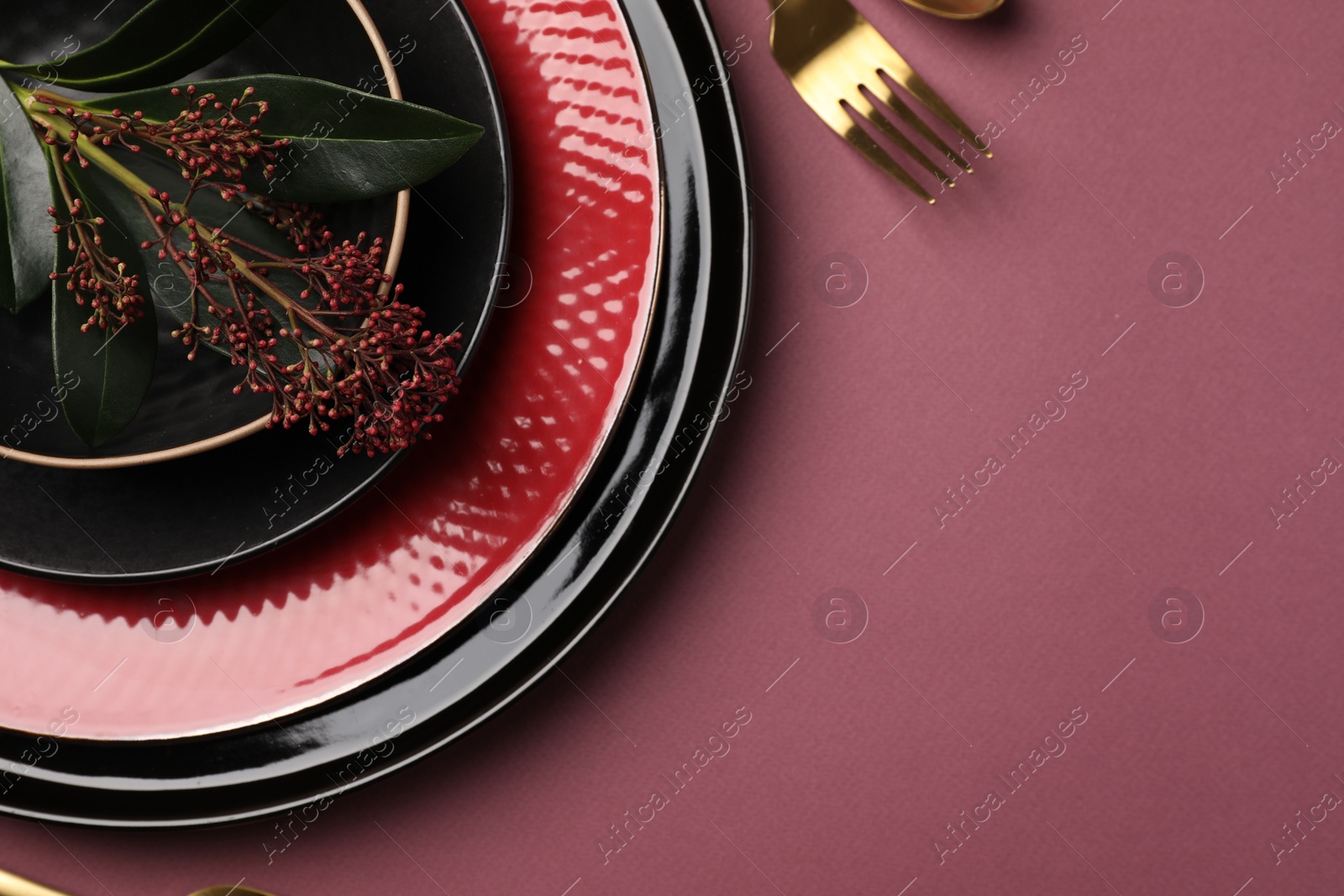 Photo of Stylish table setting with cutlery and floral decor on pink background, top view. Space for text