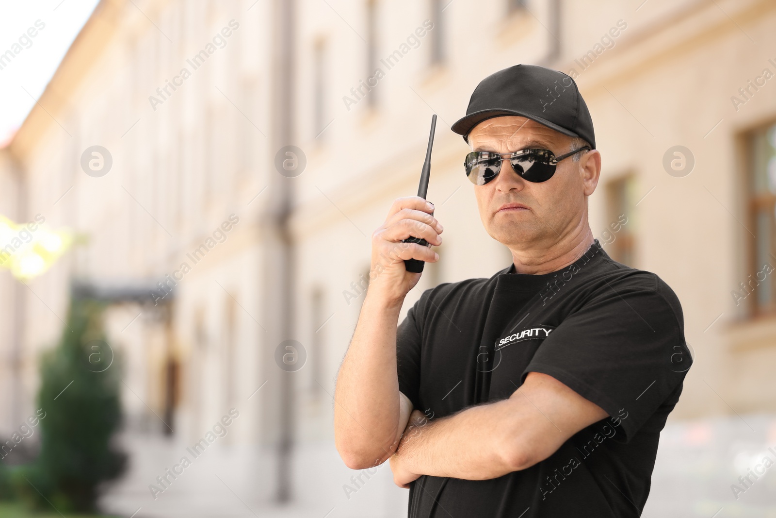 Photo of Male security guard using portable radio transmitter outdoors