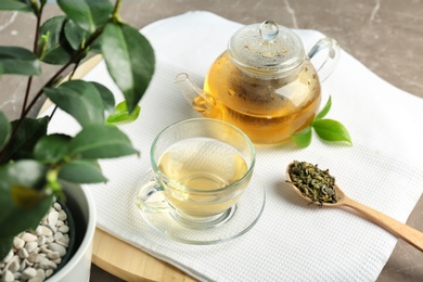 Photo of Cup of hot aromatic tea and teapot on table