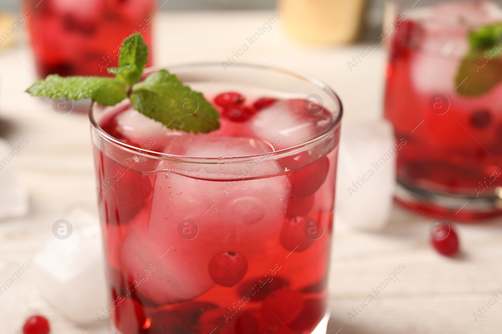 Photo of Tasty cranberry cocktail with ice cubes in glass on table, closeup