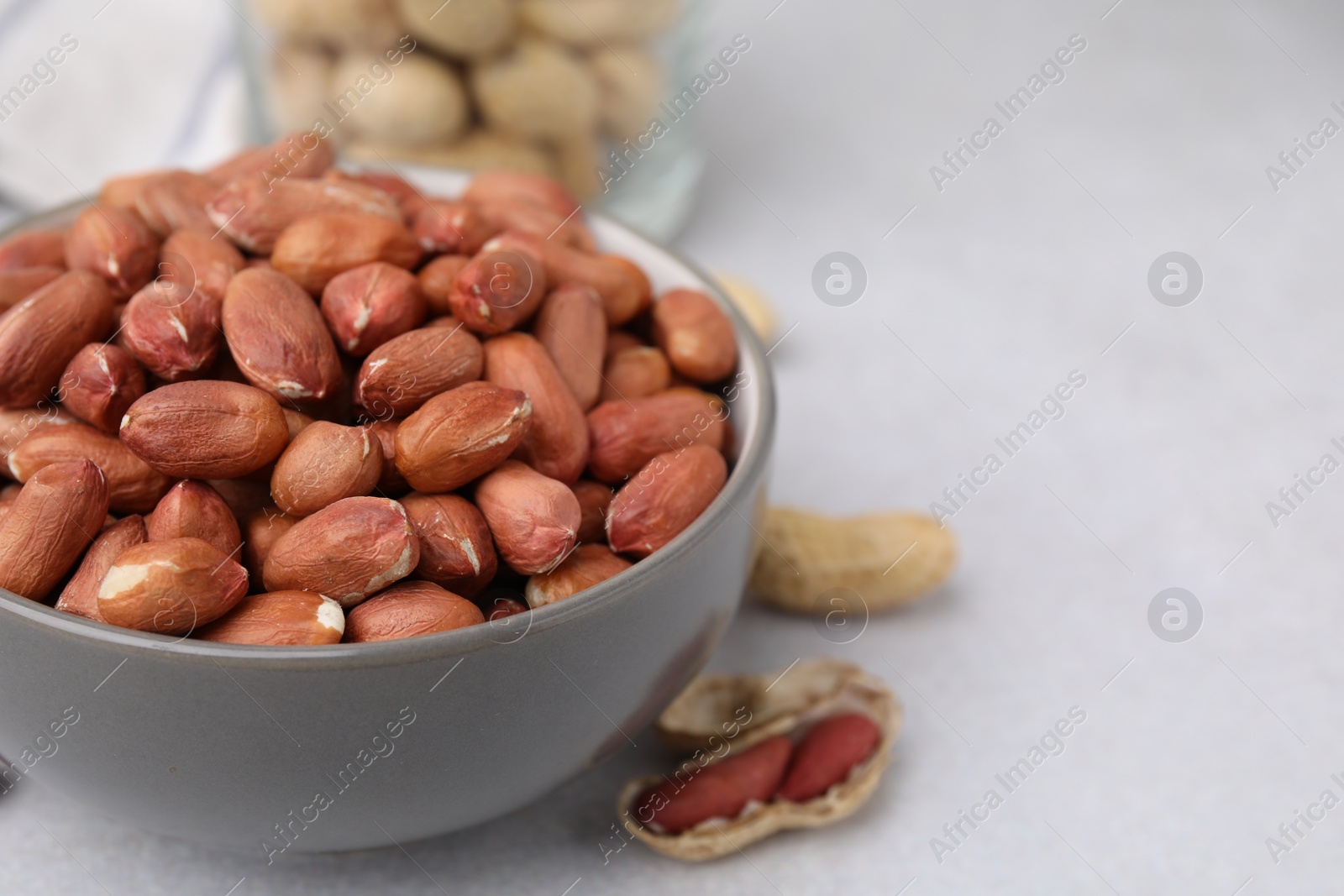 Photo of Fresh unpeeled peanuts in bowl on grey table, closeup. Space for text