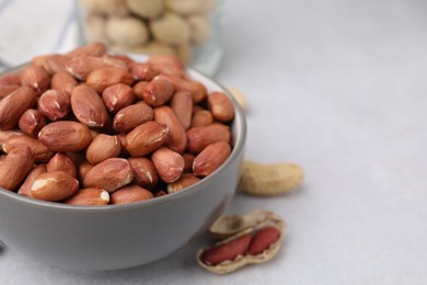 Photo of Fresh unpeeled peanuts in bowl on grey table, closeup. Space for text