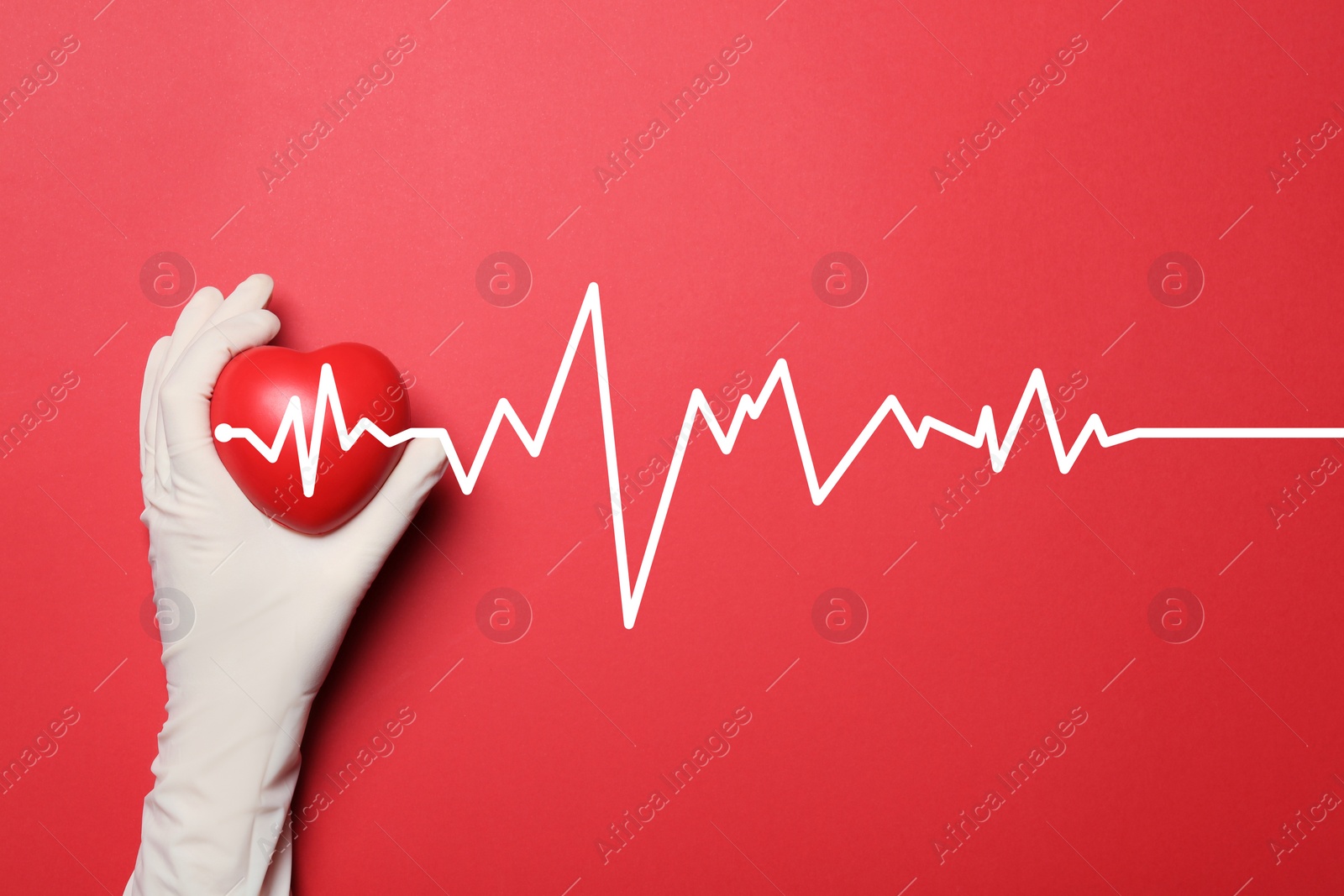 Image of Doctor in medical glove holding heart on red background, top view