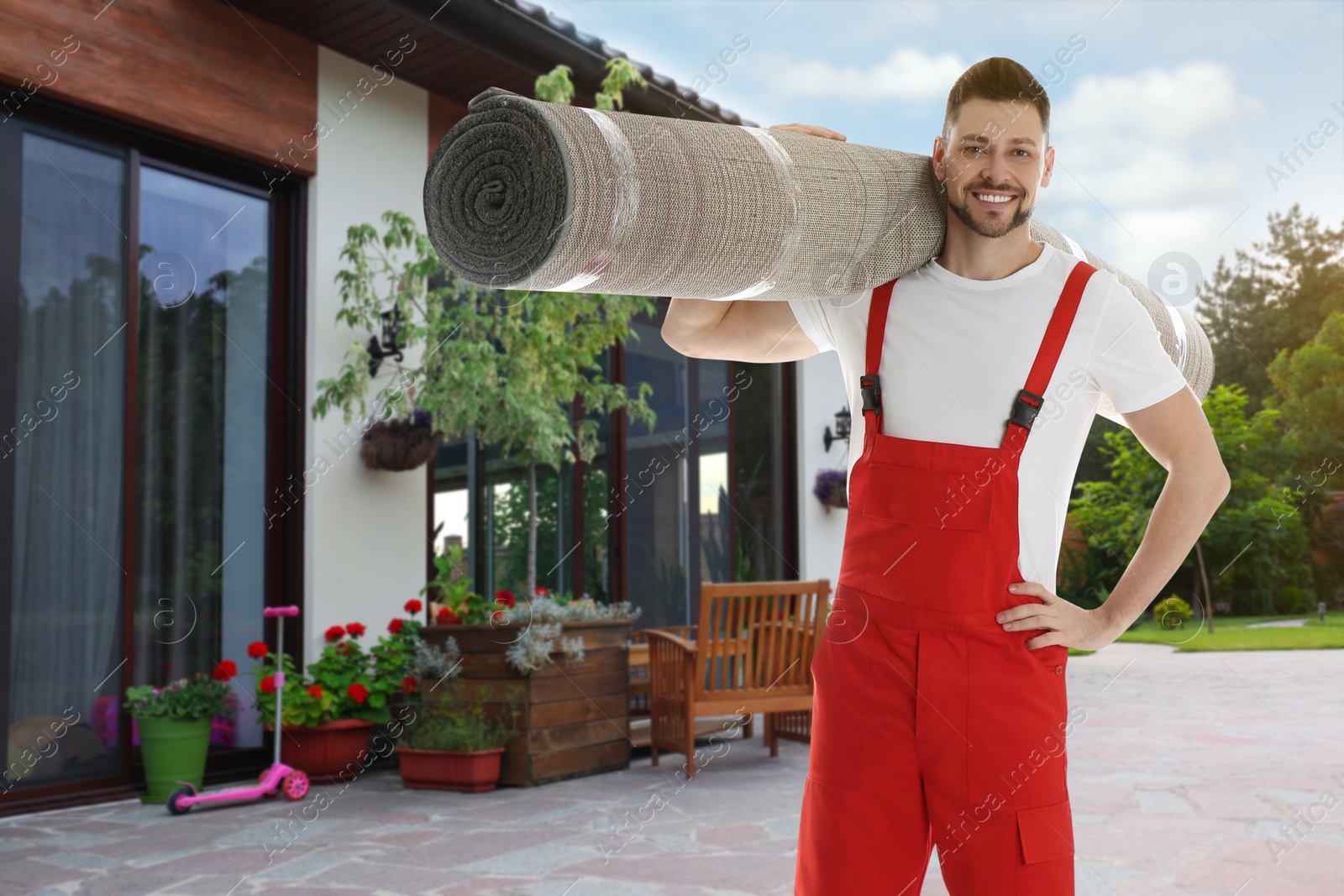 Image of Worker with rolled carpet outdoors on sunny day