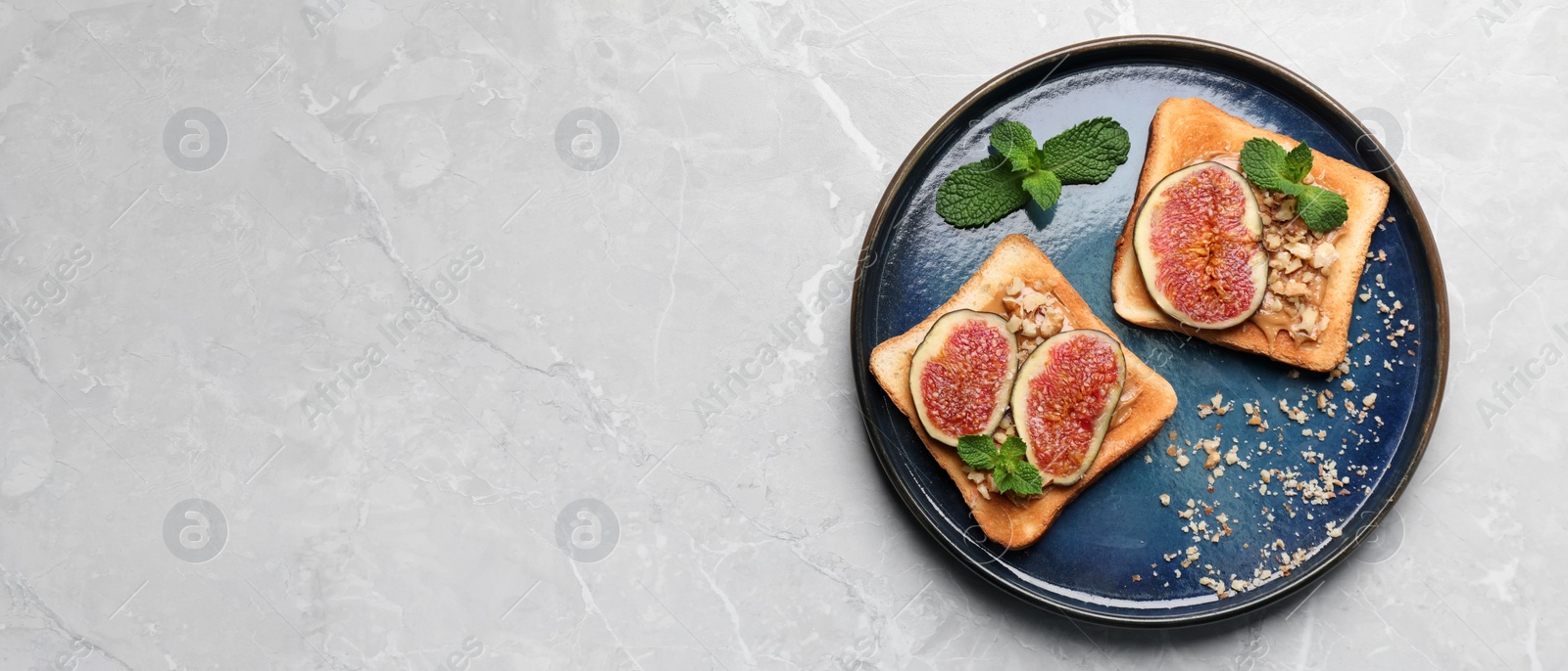 Image of Tasty toasts with fig pieces, peanut butter and walnuts on light grey marble table, top view with space for text. Banner design