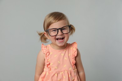 Photo of Cute little girl in glasses on light grey background