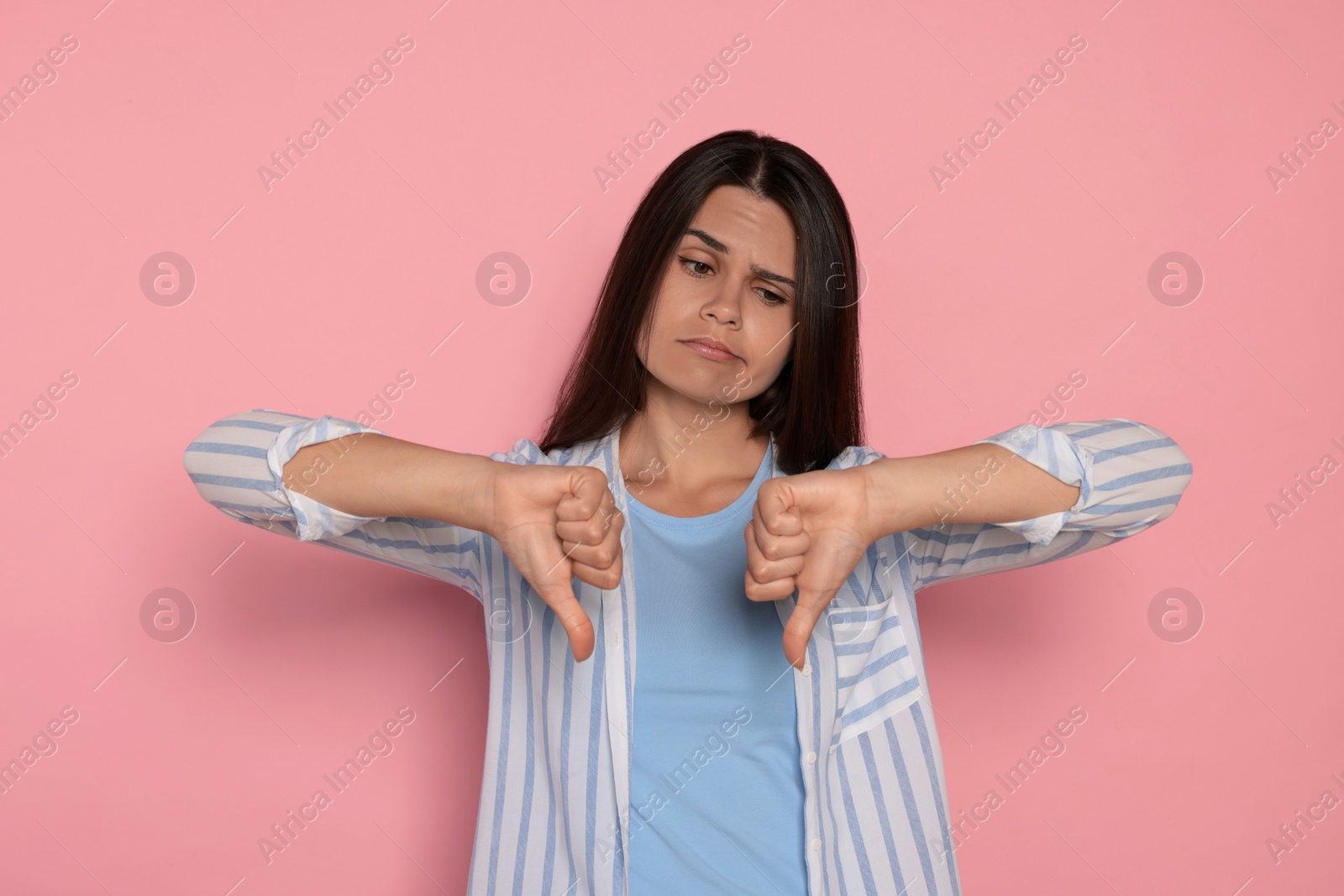 Photo of Young woman showing thumbs down on pink background