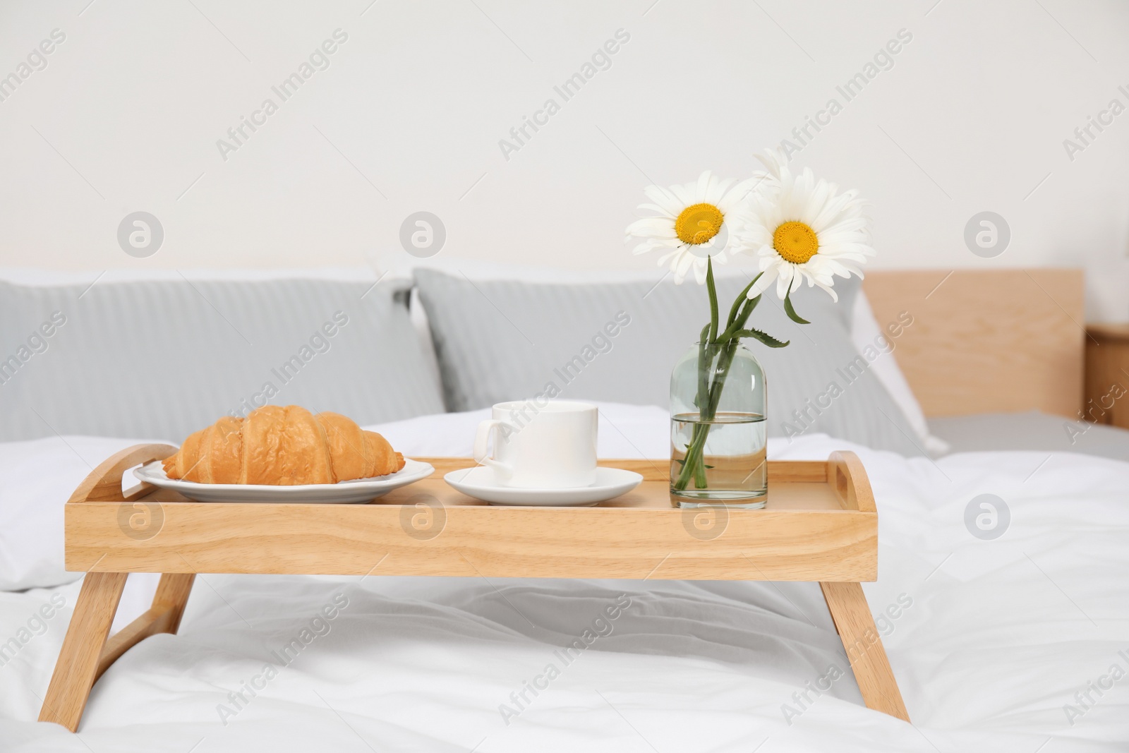 Photo of Bouquet of beautiful daisy flowers and breakfast on wooden tray in bedroom