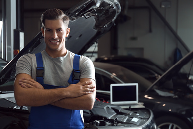 Mechanic near automobile in service center, space for text. Car diagnostic
