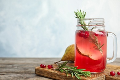 Photo of Mason jar of fresh cranberry cocktail with rosemary and space for text on light background