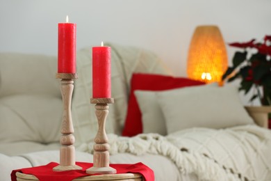 Photo of Beautiful burning candles on table in living room, space for text
