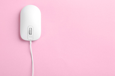 Photo of Modern wired optical mouse on pink background, top view. Space for text