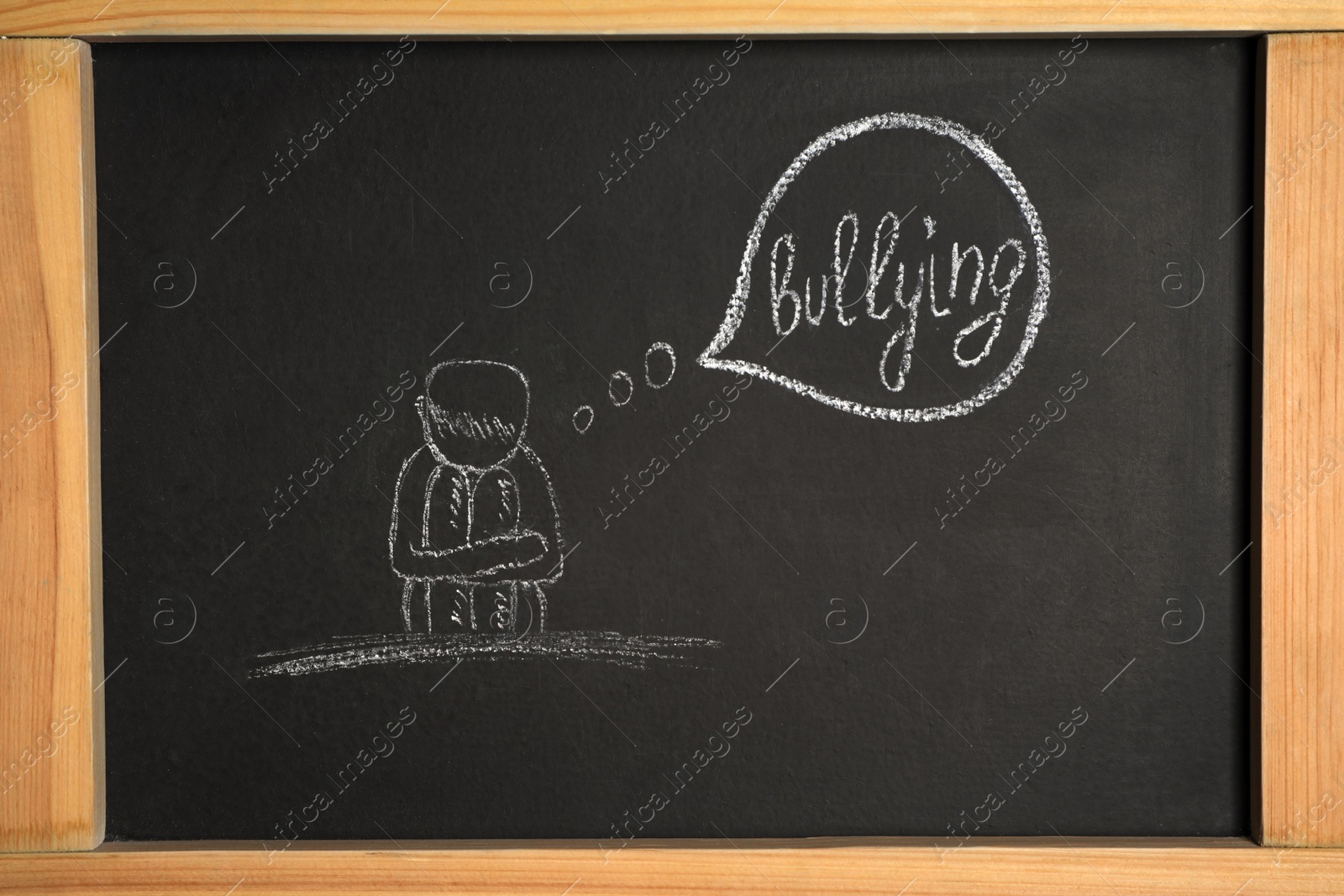 Photo of Blackboard with phrase Stop Bullying and drawing of sad human, closeup