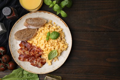 Photo of Delicious scrambled eggs with bacon and products on wooden table, flat lay. Space for text