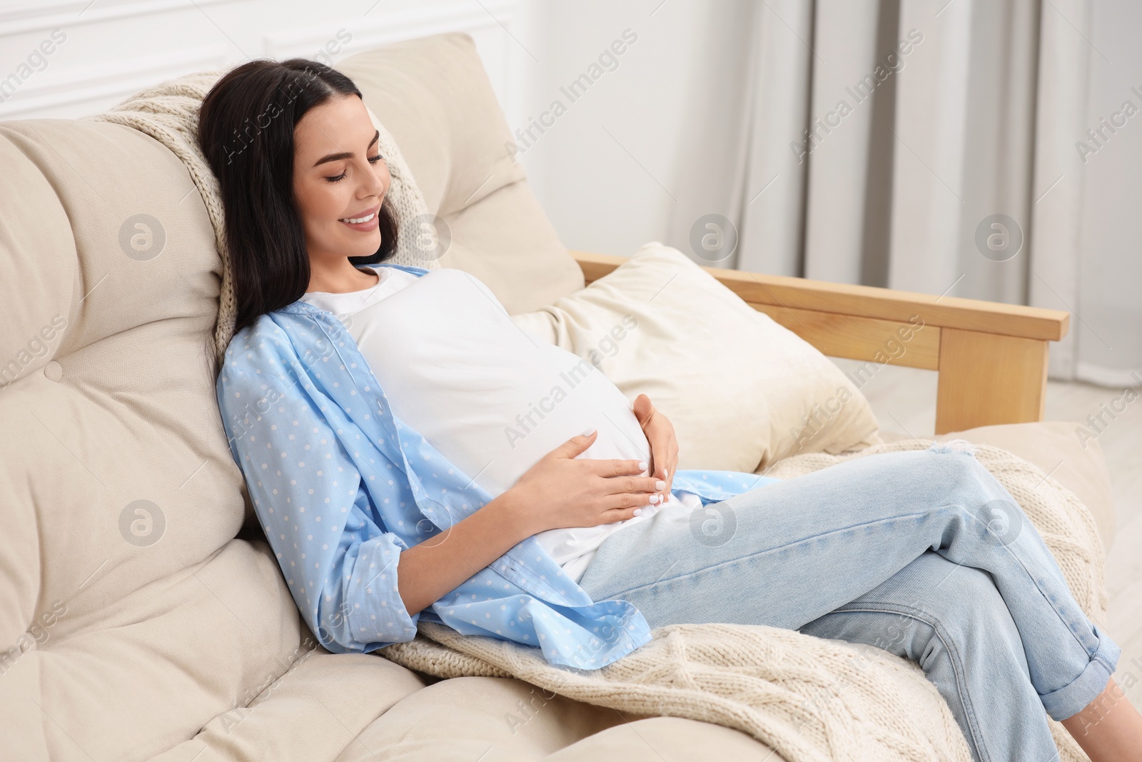 Photo of Happy pregnant woman on sofa at home