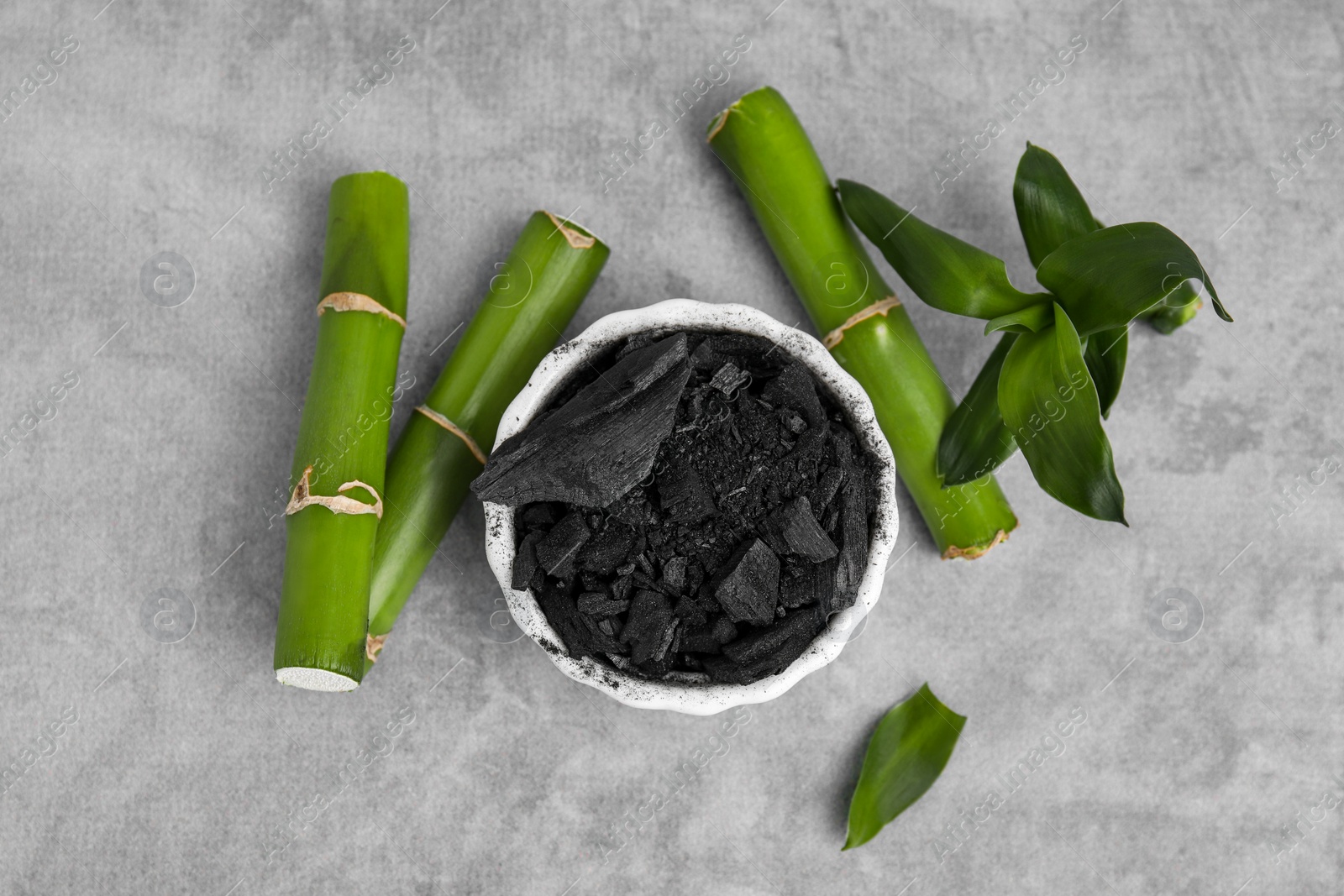 Photo of Fresh bamboo and charcoal on light gray table, flat lay