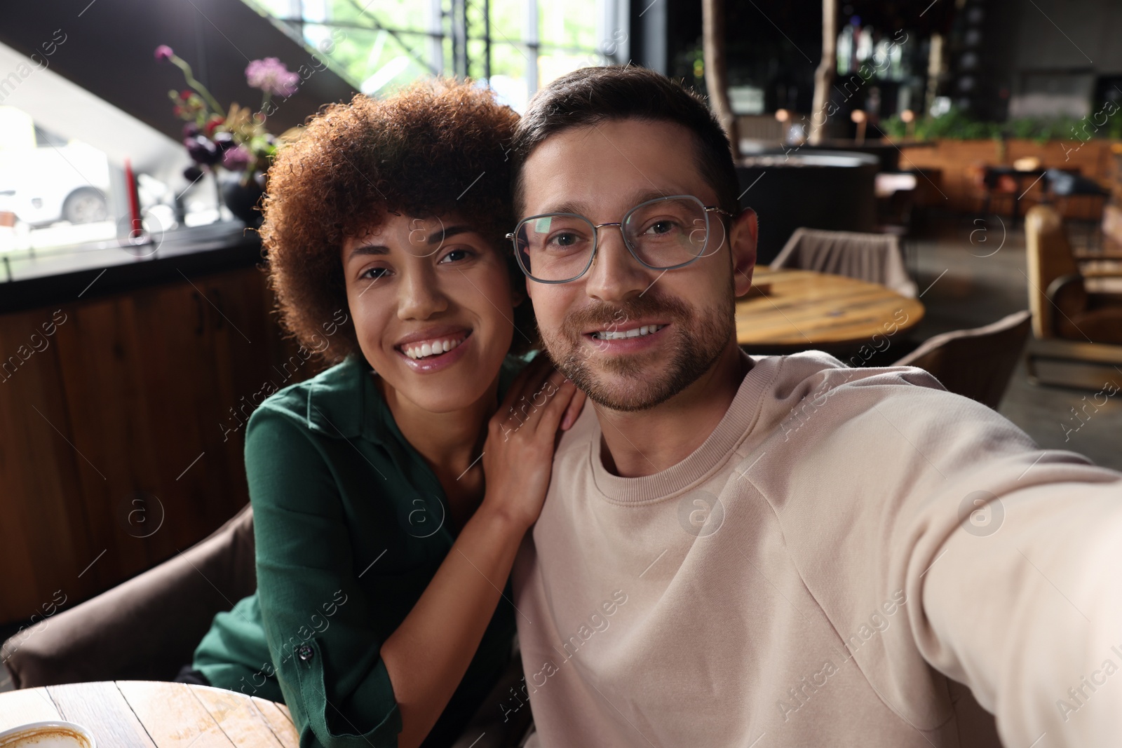 Photo of International dating. Happy couple taking selfie in cafe