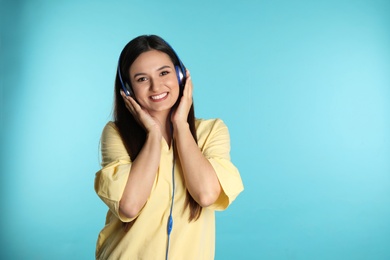 Photo of Attractive young woman enjoying music in headphones on color background. Space for text