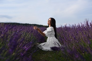 Beautiful young woman sitting in lavender field