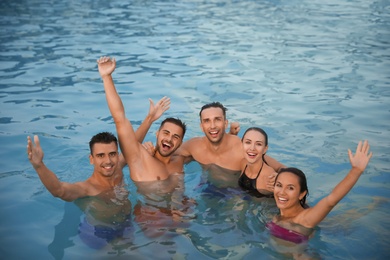 Happy young friends spending time in swimming pool
