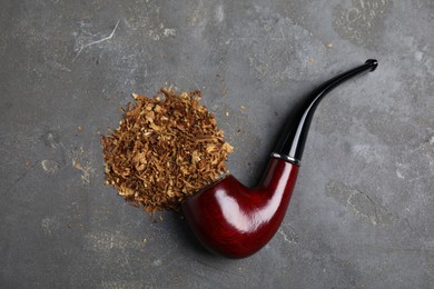 Photo of Pile of tobacco and smoking pipe on grey table, flat lay