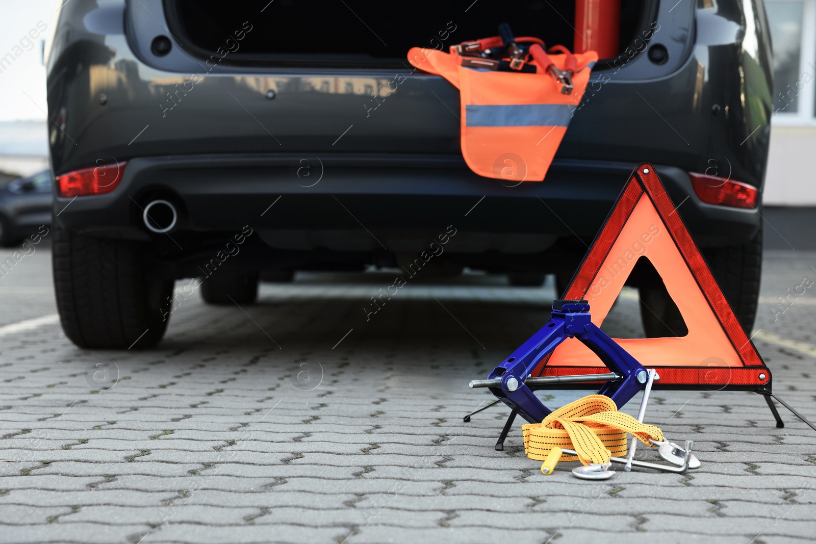 Photo of Emergency warning triangle and safety equipment near car, space for text