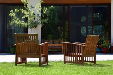 Photo of Wooden armchairs in beautiful garden on sunny day