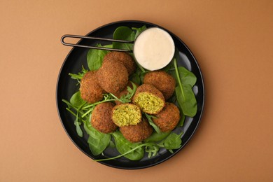 Delicious falafel balls, herbs and sauce on pale brown, top view