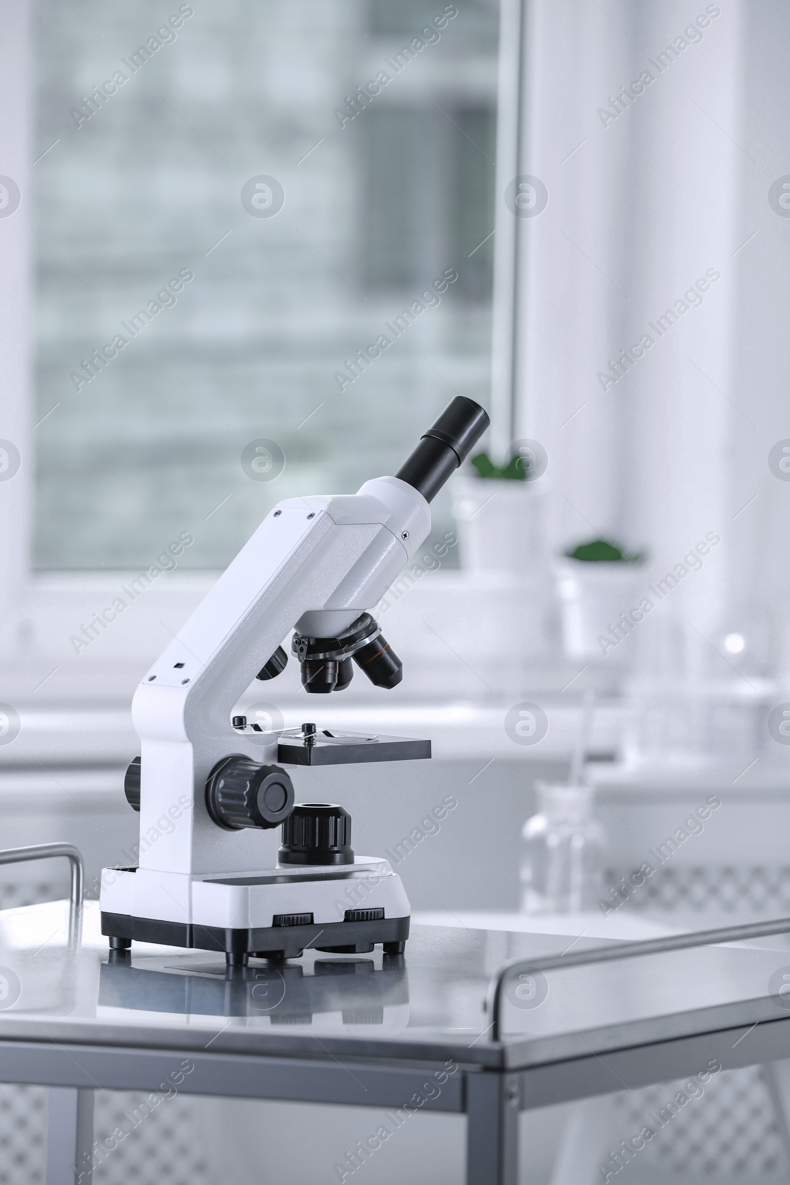 Photo of Modern medical microscope on metal table in laboratory