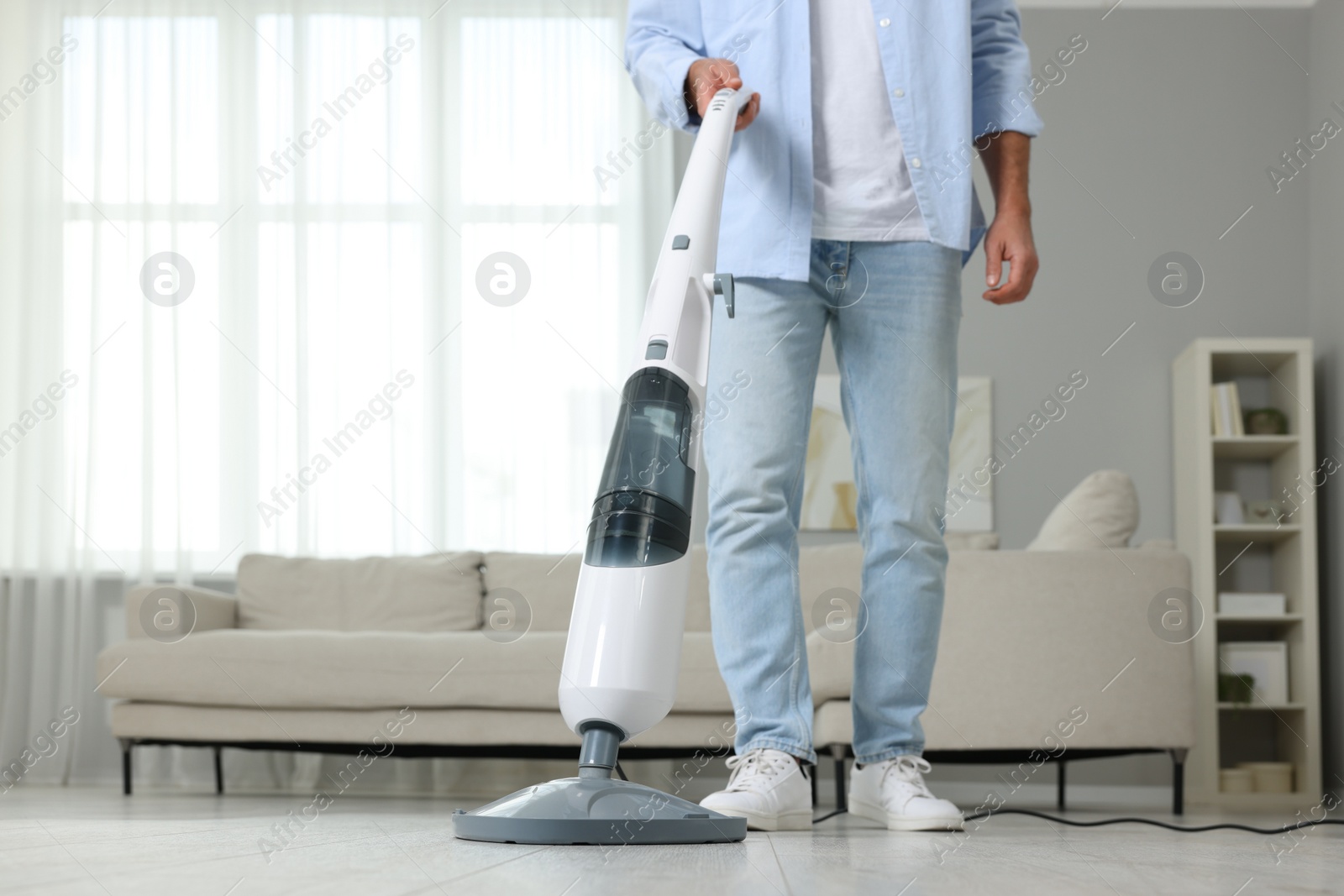 Photo of Man cleaning floor with steam mop at home, closeup. Space for text