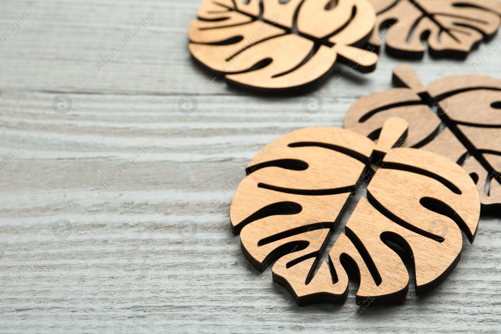 Photo of Leaf shaped wooden cup coasters on light grey table, space for text