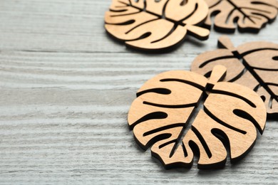Photo of Leaf shaped wooden cup coasters on light grey table, space for text