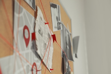 Detective board with crime scene photos and red threads, closeup