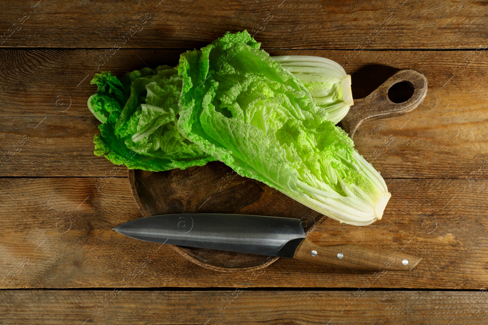 Photo of Halves of fresh ripe Chinese cabbage and knife on wooden table, flat lay