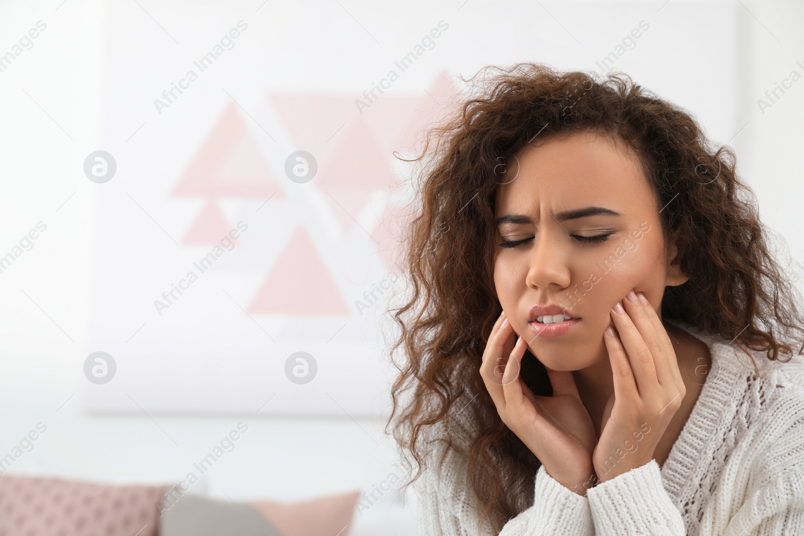 Photo of African-American woman suffering from tooth ache indoors. Space for text