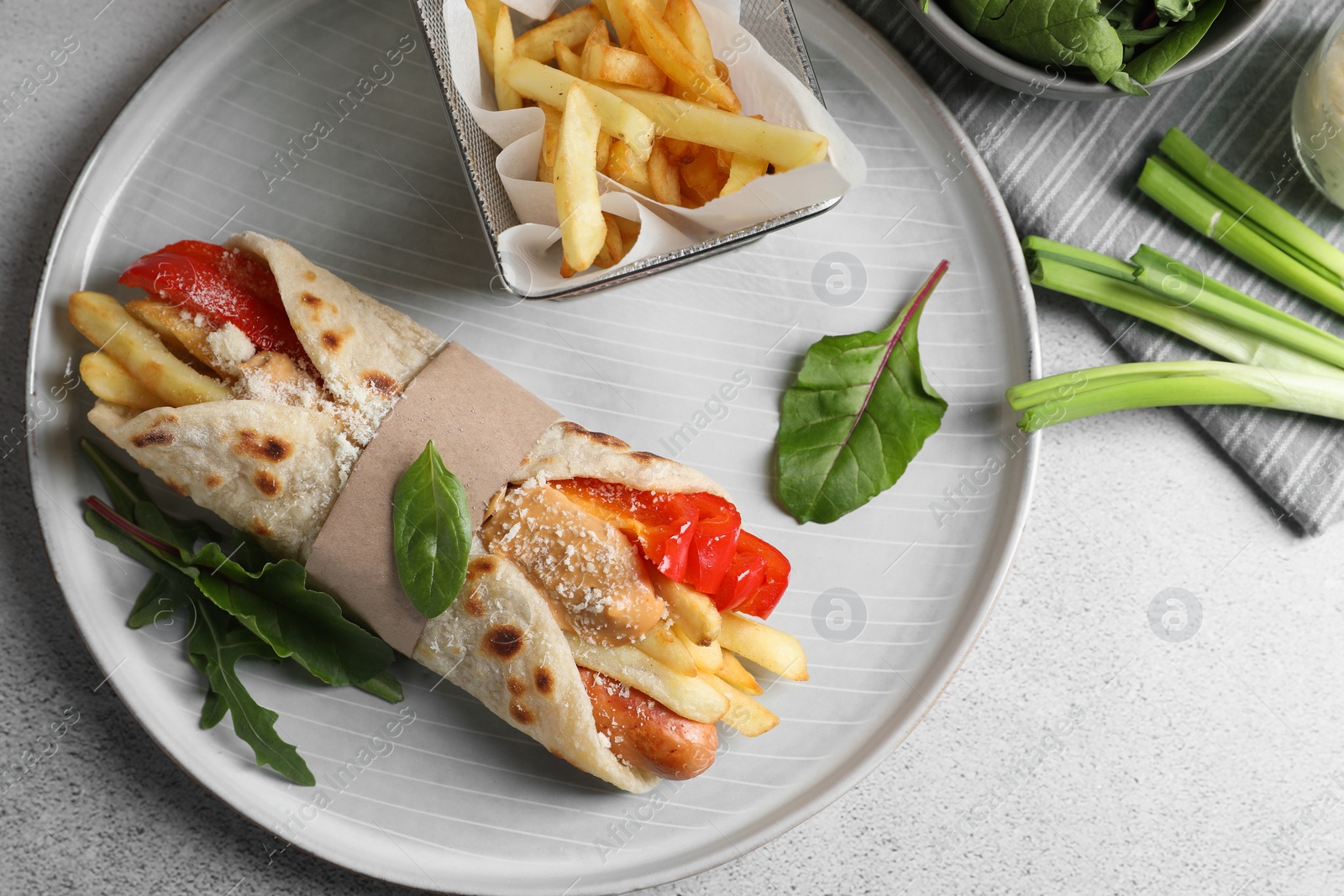 Photo of Delicious pita wrap with sausage, french fries and pepper on light gray table, flat lay