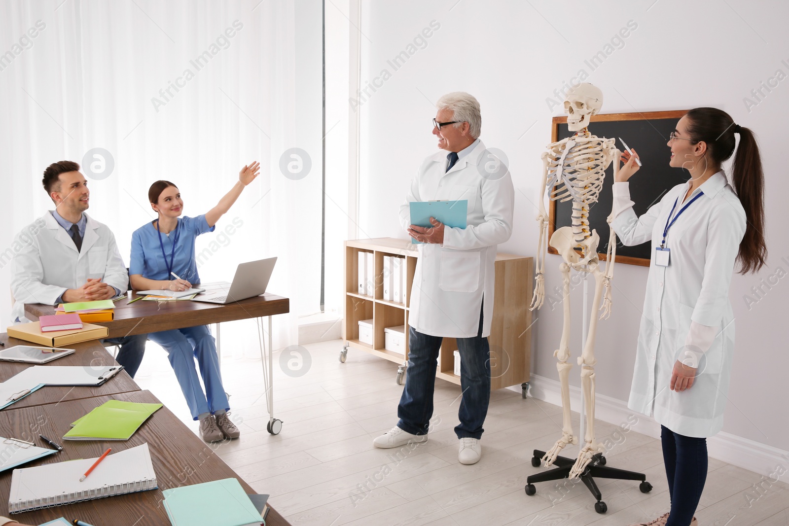 Photo of Medical students and professor studying human skeleton anatomy in classroom