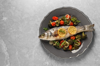 Photo of Baked fish with vegetables and lemon on grey textured table, top view. Space for text