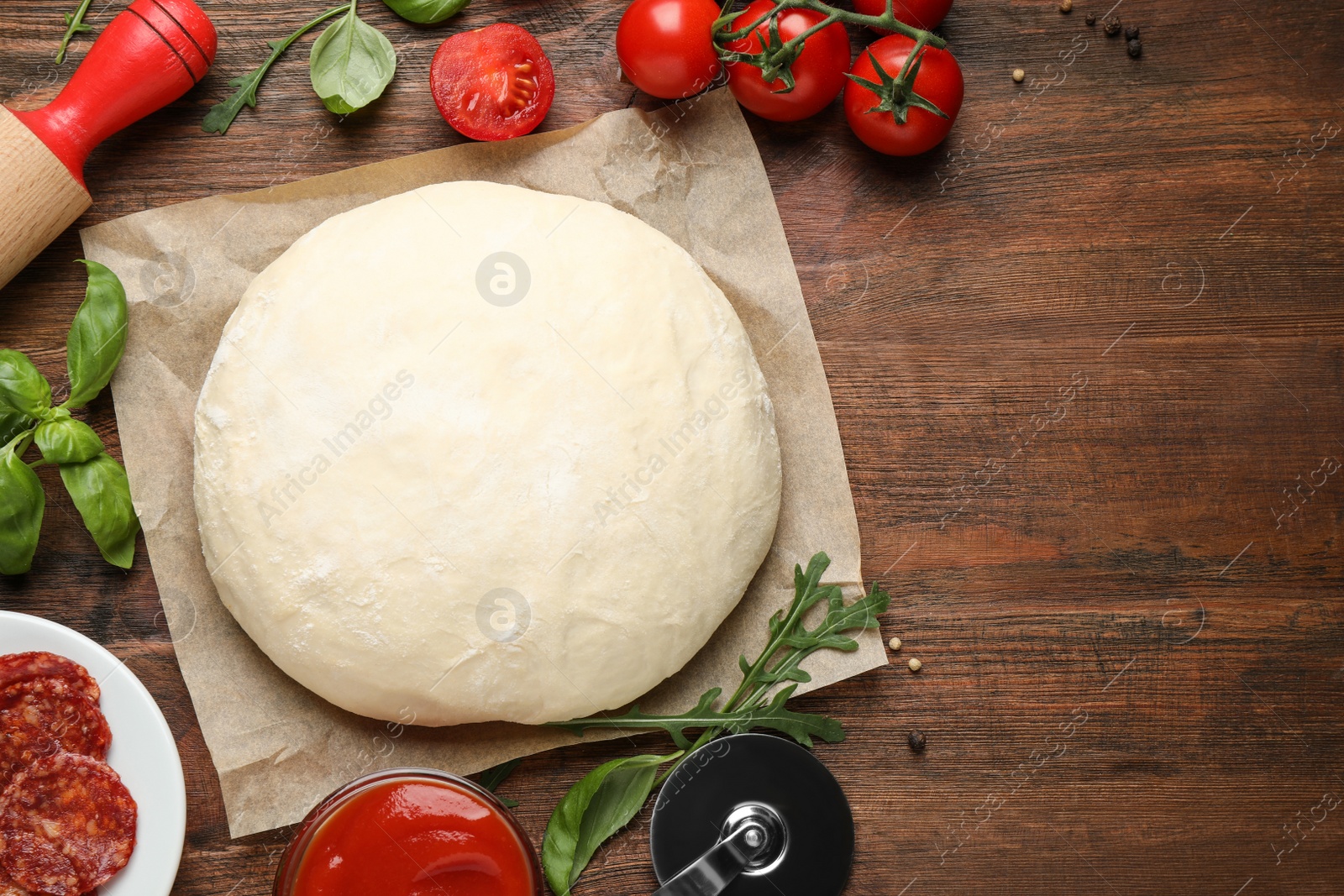 Photo of Flat lay composition with dough and ingredients on wooden table, space for text. Pepperoni pizza recipe