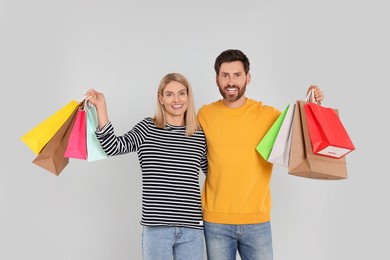 Family shopping. Happy couple with many colorful bags on light grey background