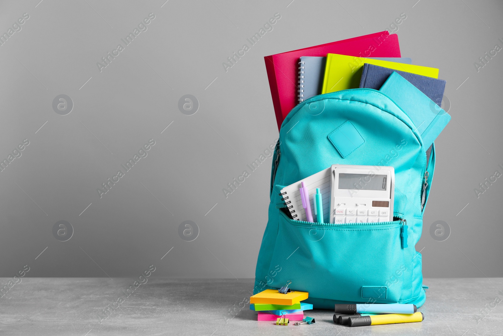 Photo of Turquoise backpack and different school stationery on table against grey background, space for text