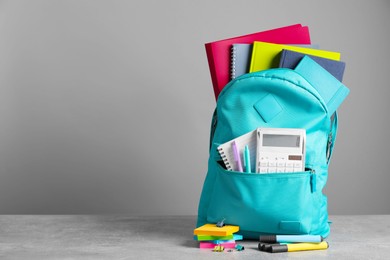 Photo of Turquoise backpack and different school stationery on table against grey background, space for text