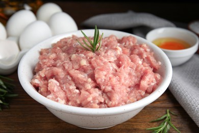 Photo of Raw chicken minced meat with rosemary on wooden table, closeup