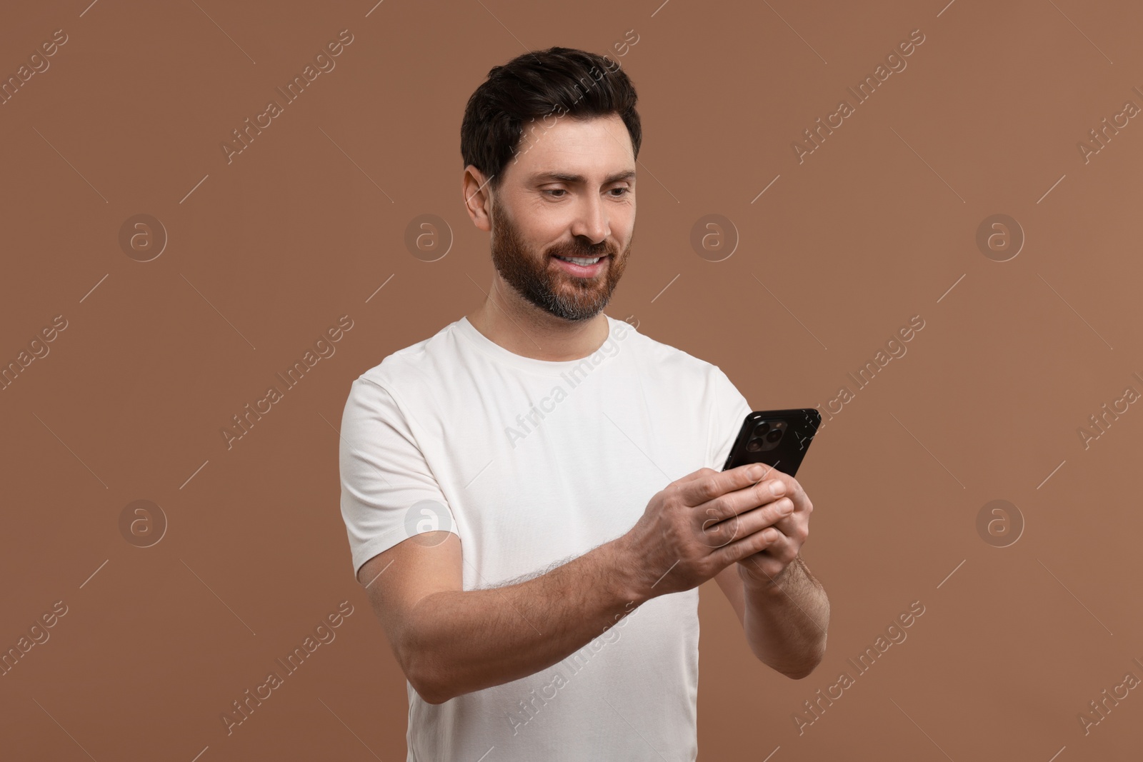 Photo of Smiling man with smartphone on light brown background