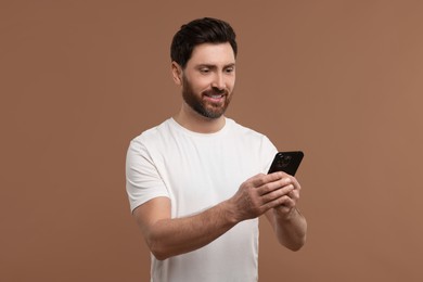 Photo of Smiling man with smartphone on light brown background