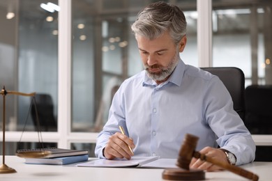 Serious lawyer working at table in office, space for text