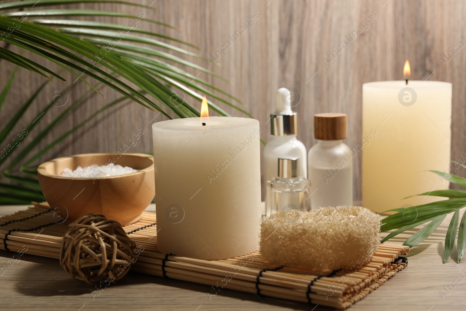 Photo of Composition with spa supplies and palm leaves on wooden table